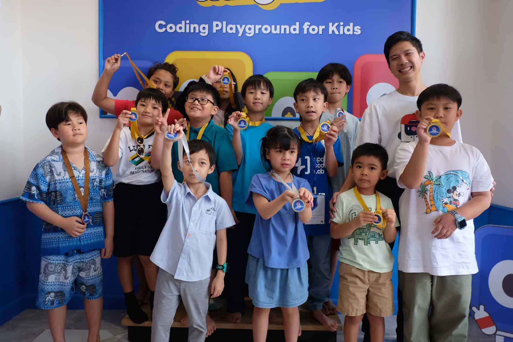 เยาวชนถือเหรียญถ่ายภาพร่วมกันที่ Coding Playground